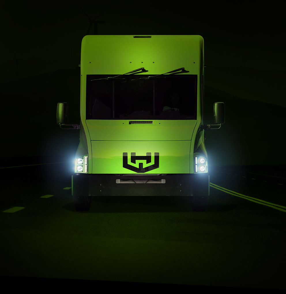 Green Workhorse truck driving forward on road with headlights on